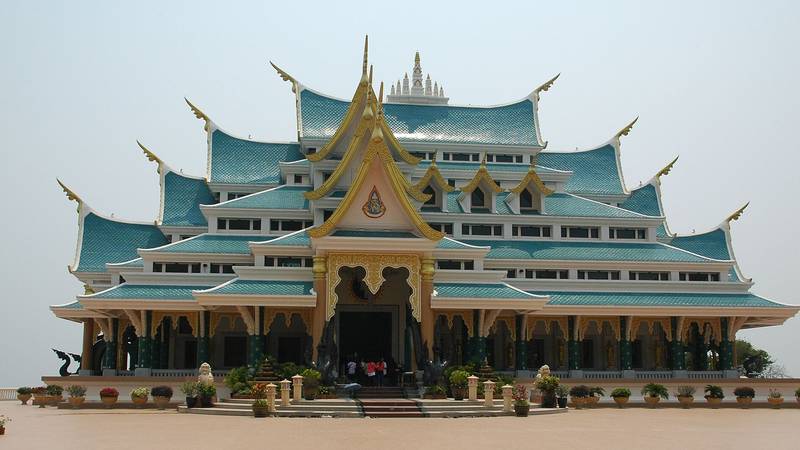 พระวิหารหลังคาซ้อนหลายชั้นสีฟ้าอมเขียว ตกแต่งลายไทยสีทองบนลานกว้าง
